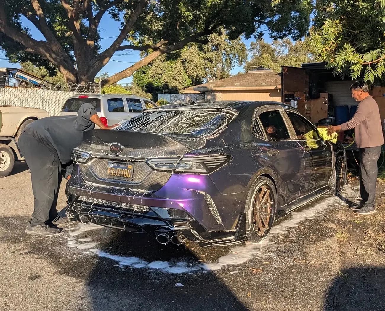 Rear three-quarter of a Camry being washed by two detailers
