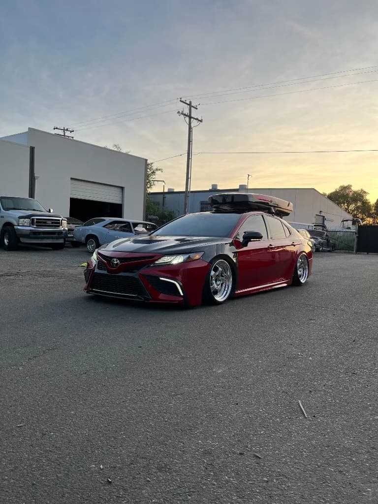 Red slammed Toyota Camry with roof box, front three-quarter after detailing