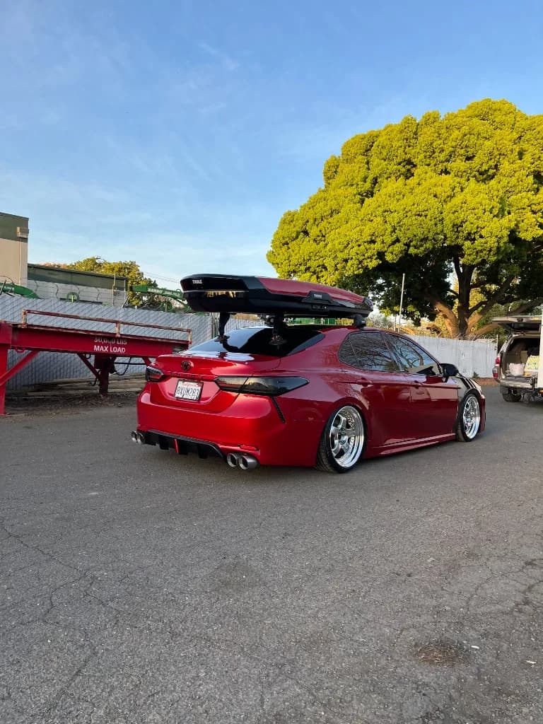 Rear three-quarter of a red slammed Toyota Camry at dusk after detailing