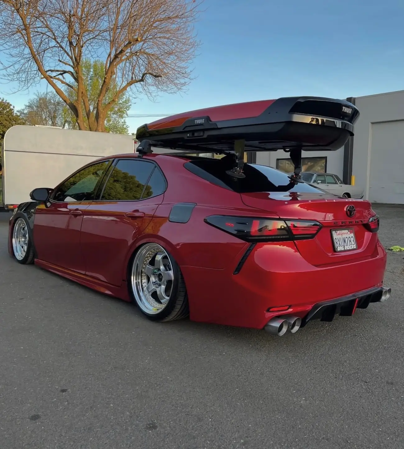 Rear three-quarter view of a red Toyota Camry with roof box after detailing