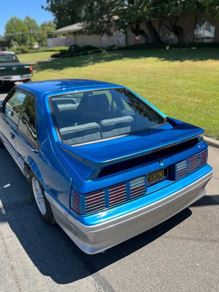 Rear view of a blue Fox-body Mustang 5.0 after exterior detailing