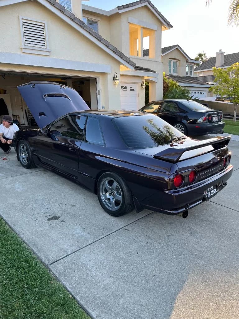 Three-quarter rear view of a dark purple Nissan Skyline R32 after detailing